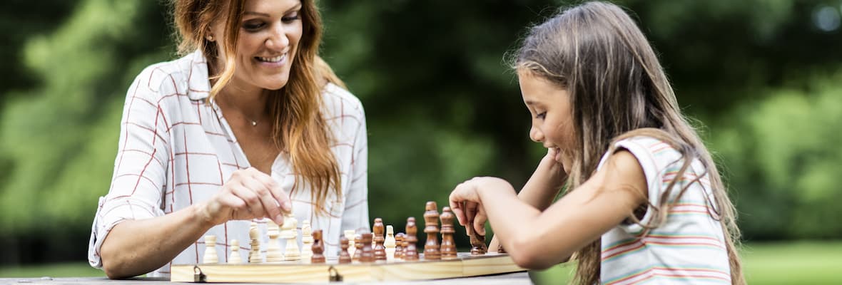Mother and daughter play chess in the park 