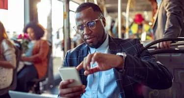 businessman checks phone on bus while commuting to work
