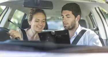 Young woman receives feedback from male driving instructor