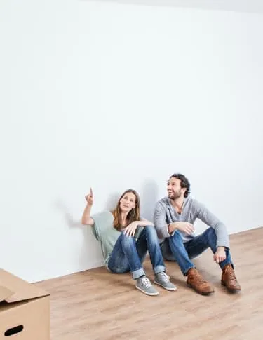 Couple sitting on the floor of their new home surrounded by moving boxes