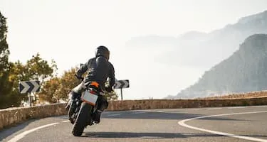 Motorcyclist riding along range drive on mountains