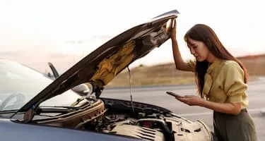 Woman looking at phone while opening car bonnet
