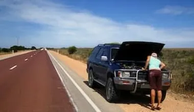 A 4x4 is broken down on the side of an outback road, being checked by the driver