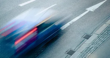Car speeding dangerously along road.