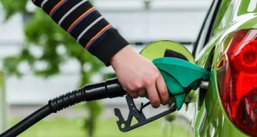 Close up of a hand with a fuel pump in a car.