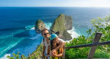 Young couple stands on the stairs above Kelingking beach near Bali.