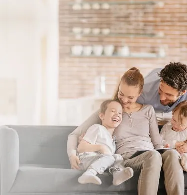 Mother and father laughing with their two children on the couch