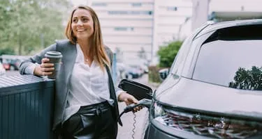 Smiling business woman charging electric car