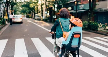 young boy with helmet in child seat of bike with mum riding through streets