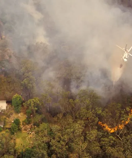 Helicopter releasing water over a bushfire