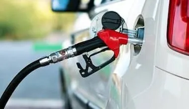 Fuel pump handle sticking out of fuel tank opening in car.