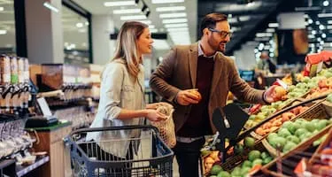 A young couple shops for oranges in grocery store.