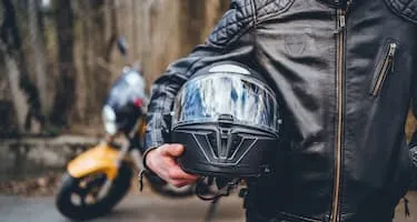 Motorcyclist holds helmet outside