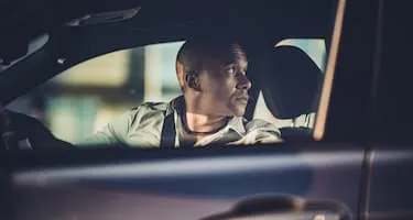 man looks nervously over shoulder while reversing car