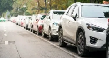 Cars parked along the side of empty suburban road.