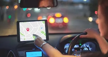 Woman points at screen in car while driving at night
