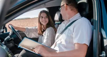 Young woman learns to drive from male driving instructor