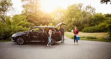 mum dad and daughter packing car boot with esky and ball
