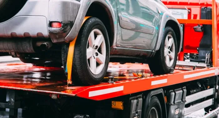 A car is secured to the bed of a tow truck