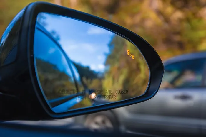 Close up of car wing mirror with sensor light lit up