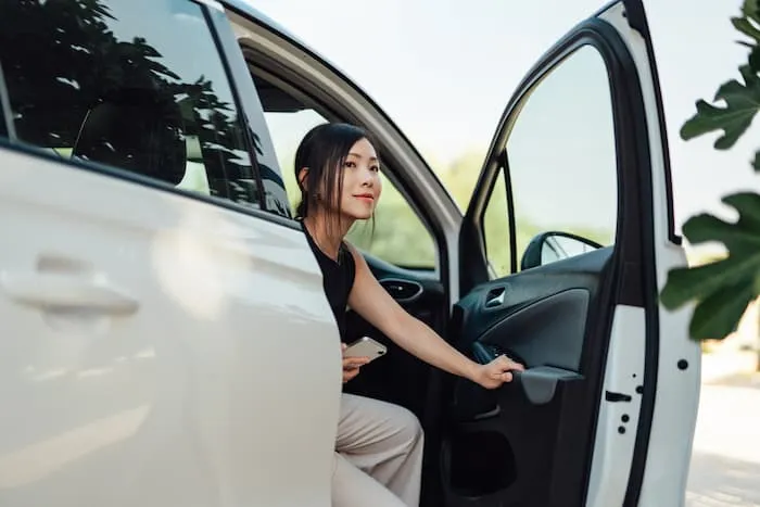 Young woman sits with the rental car door open