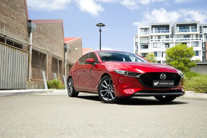 Red Mazda 3 parked in front of inner city apartments