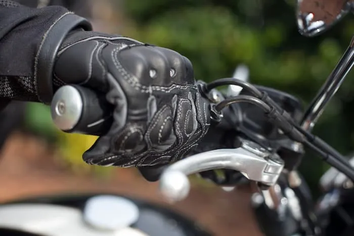 Hands wearing motorcycle gloves hold the motorbike’s throttle grip