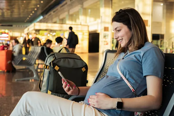 Happy pregnant woman waiting for transport at a train station.