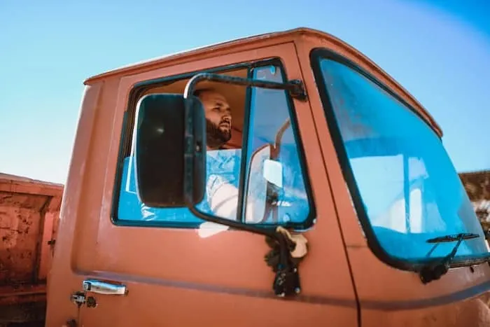 A truck driver checks his side mirror for blind spots while driving.