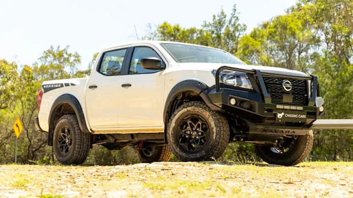 white Nissan Navara parked on dead grass outside