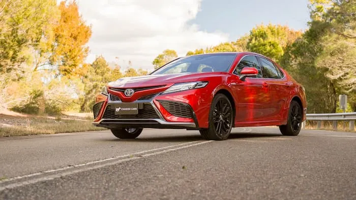 A Red Toyota Camry SX Hybrid is parked on the road