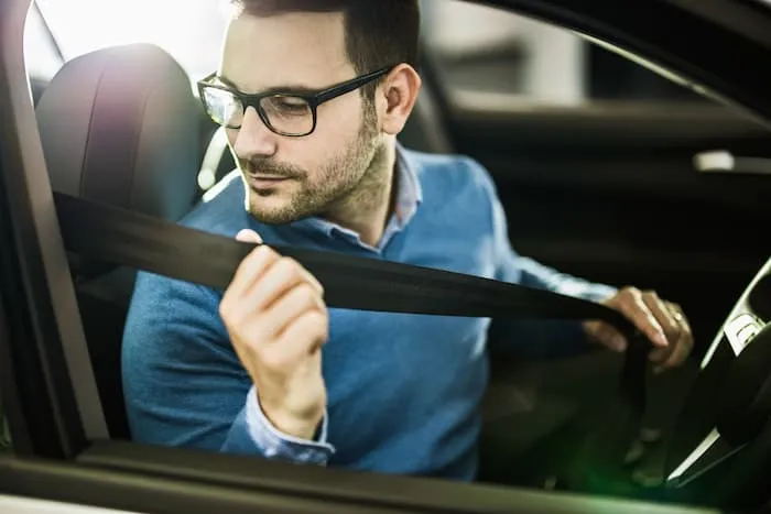 Young man fastens his seat belt before a car trip