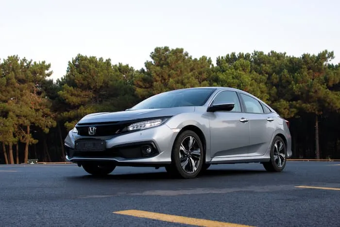 silver Honda Civic parked in carpark in front of forest