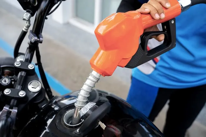 A motorcyclist refills petrol into a motorcycle barrel tank
