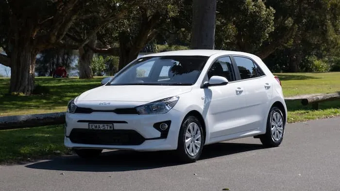 white kia rio parked on side of the road out the front of park