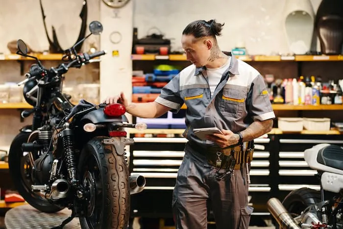A mechanic performs a pre-purchase inspection for a customer looking to buy a motorcycle.