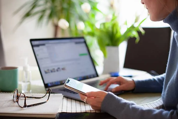 Man sitting at desk and looking at phone while doing bills