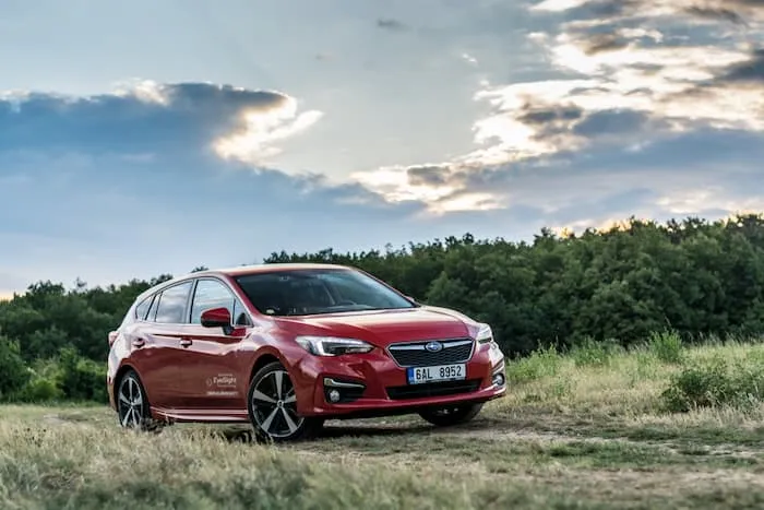 red Subaru Impreza driving on dirt track outside