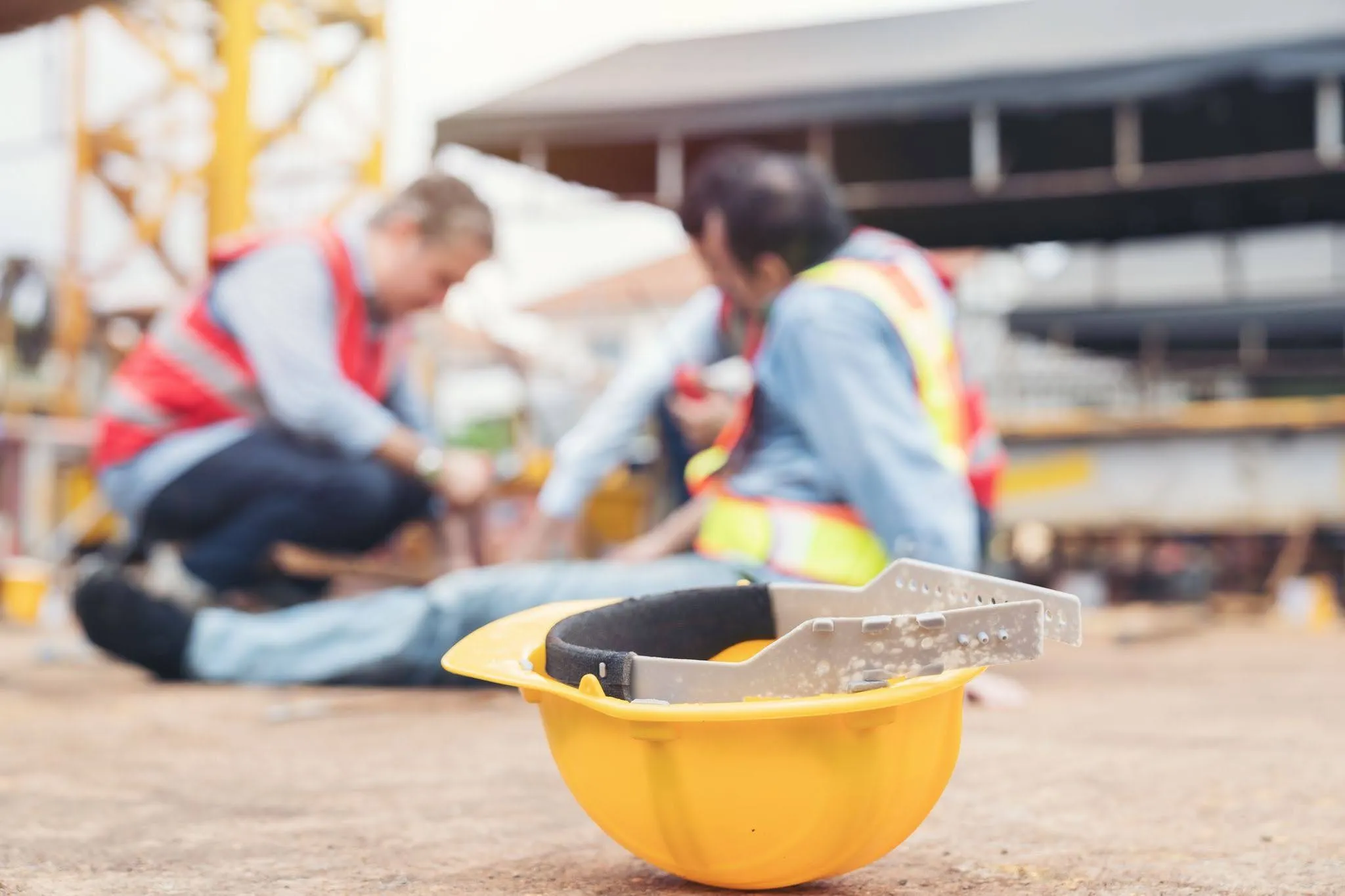 Construction builder worker accident at construction site. A hard hat is in the foreground