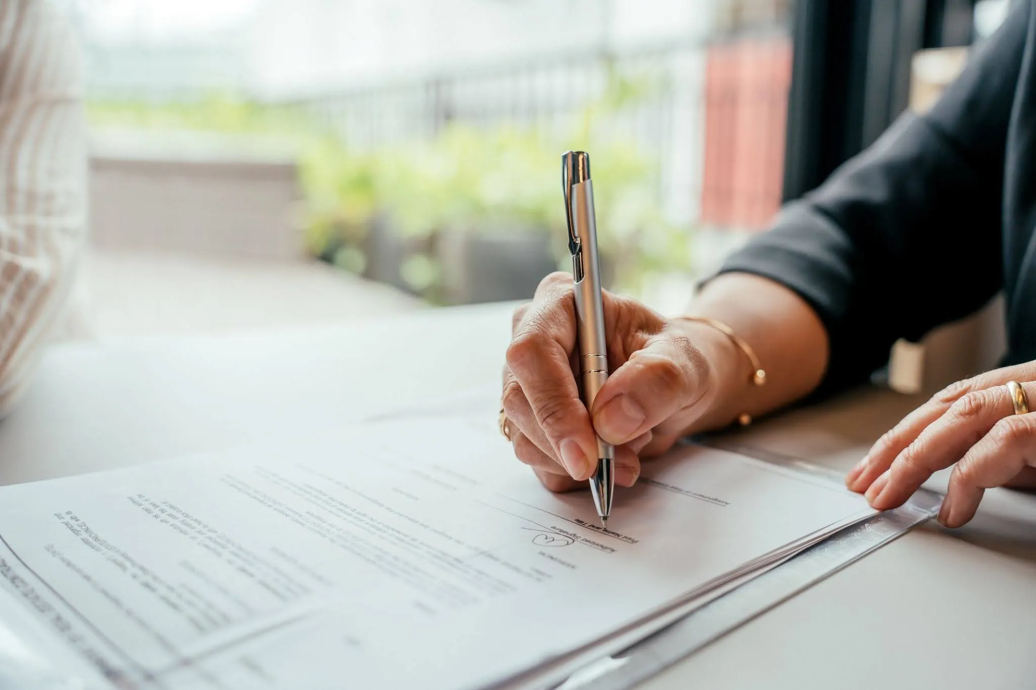 A close up of a hand signing documents with a pen