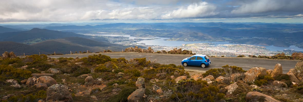 A small blue car drives on top of Mount Wellington above Tasmania's capital city, Hobart. 