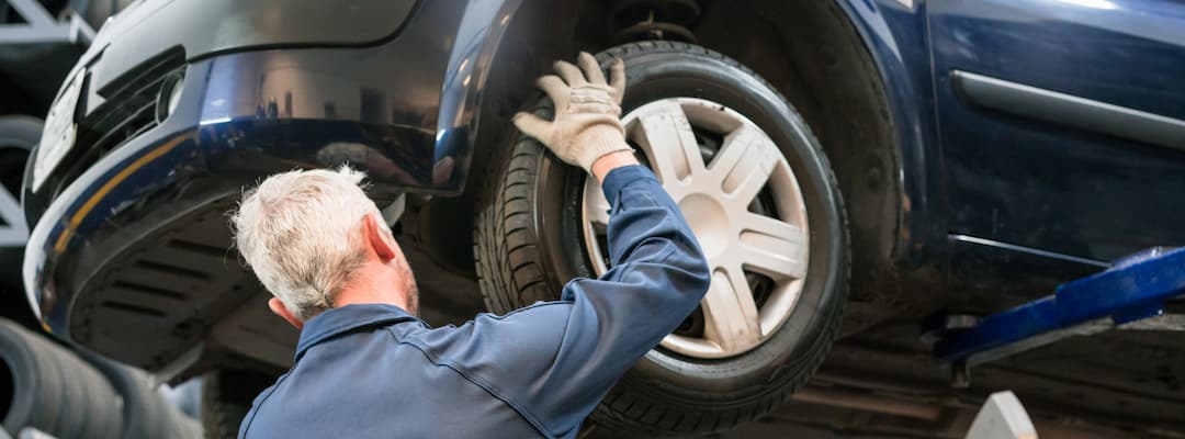  A man uses a vehicle hoist to replace car tyres
