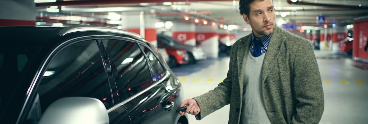 Young man locks his car using a remote key in the car park