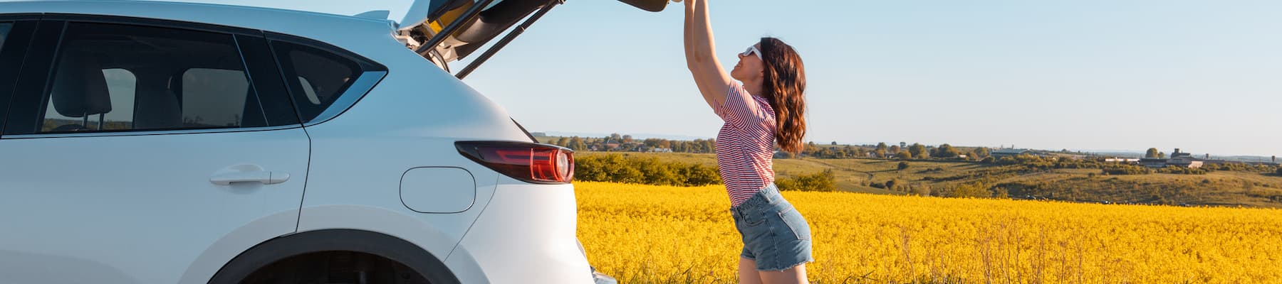 woman closing boot of white SUV parked in field