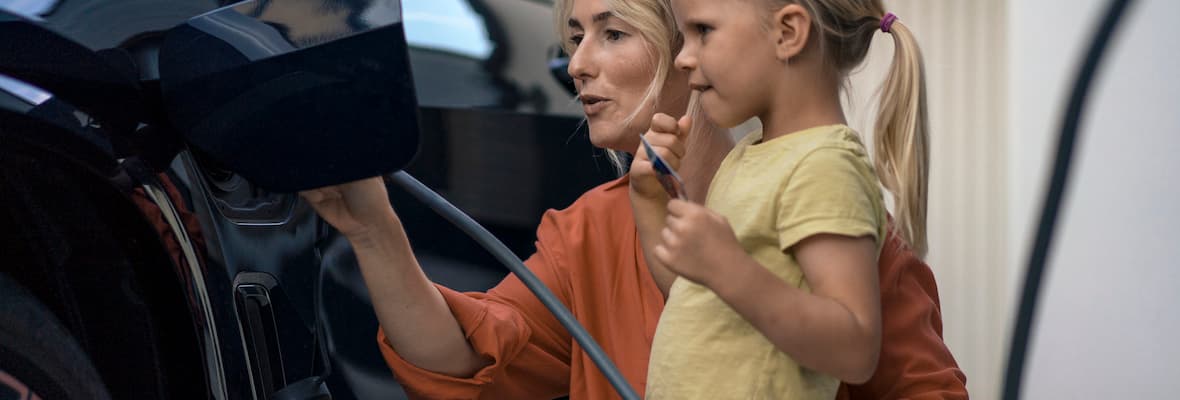 Young girl and her mum charge an electric vehicle at home