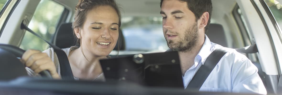 Young woman receives feedback from male driving instructor