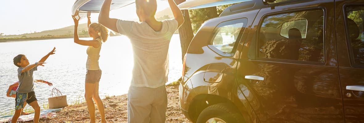 family unpacks car with sporting equipment at beach