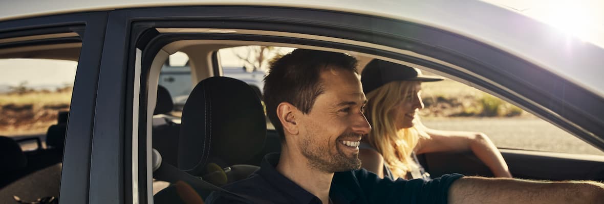 man and woman smile while driving along outback road