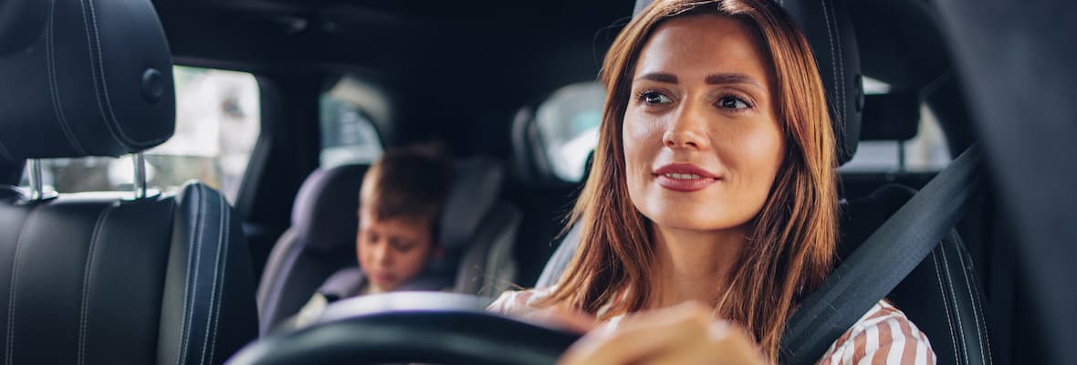  A woman fastens her seatbelt while seated behind the driver’s seat of a car