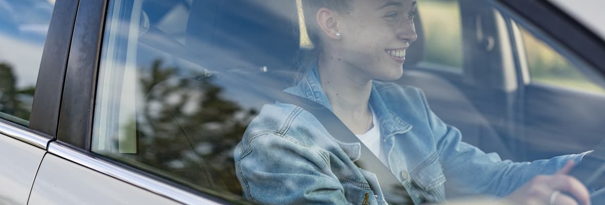 Proud young woman driving her first car